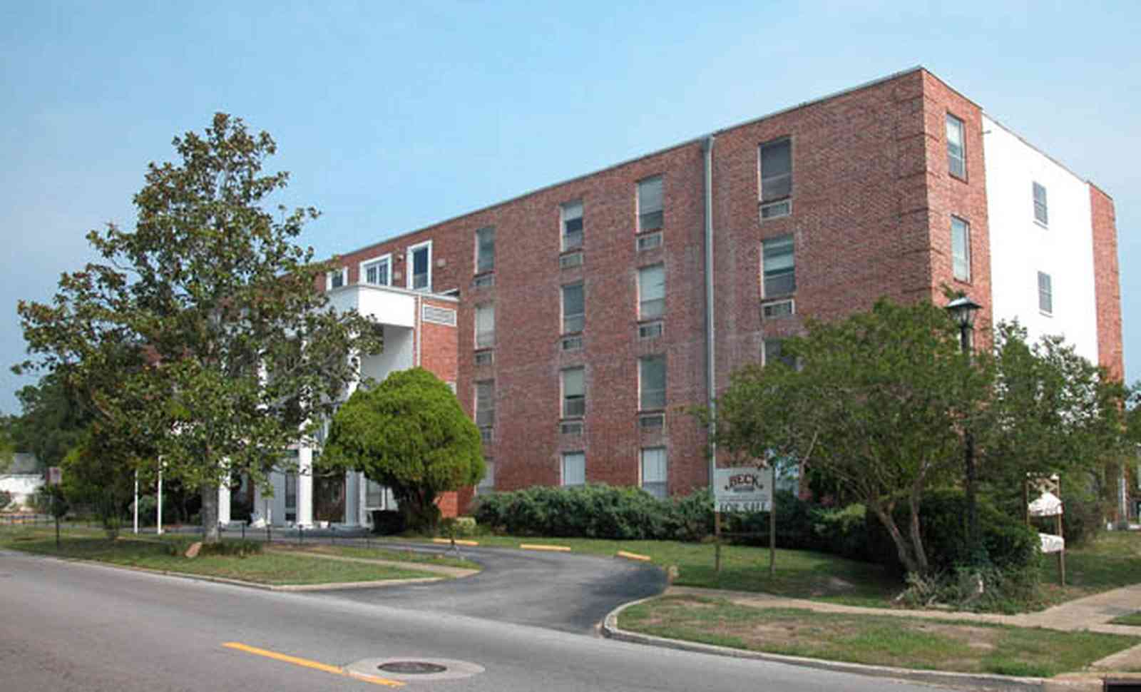 Belmont-Devillers:-The-Magnolias_01.jpg:  magnolia tree, fir tree, columns, brick building, nursing home, apartment building, 