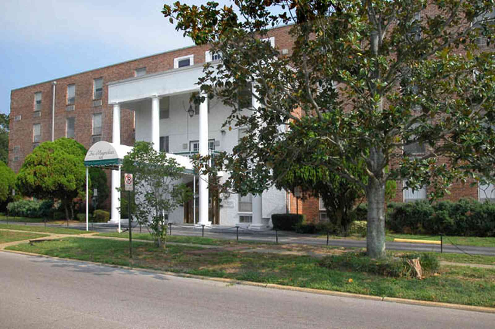 Belmont-Devillers:-The-Magnolias_02.jpg:  magnolia tree, fir tree, columns, brick building, nursing home, apartment building, 