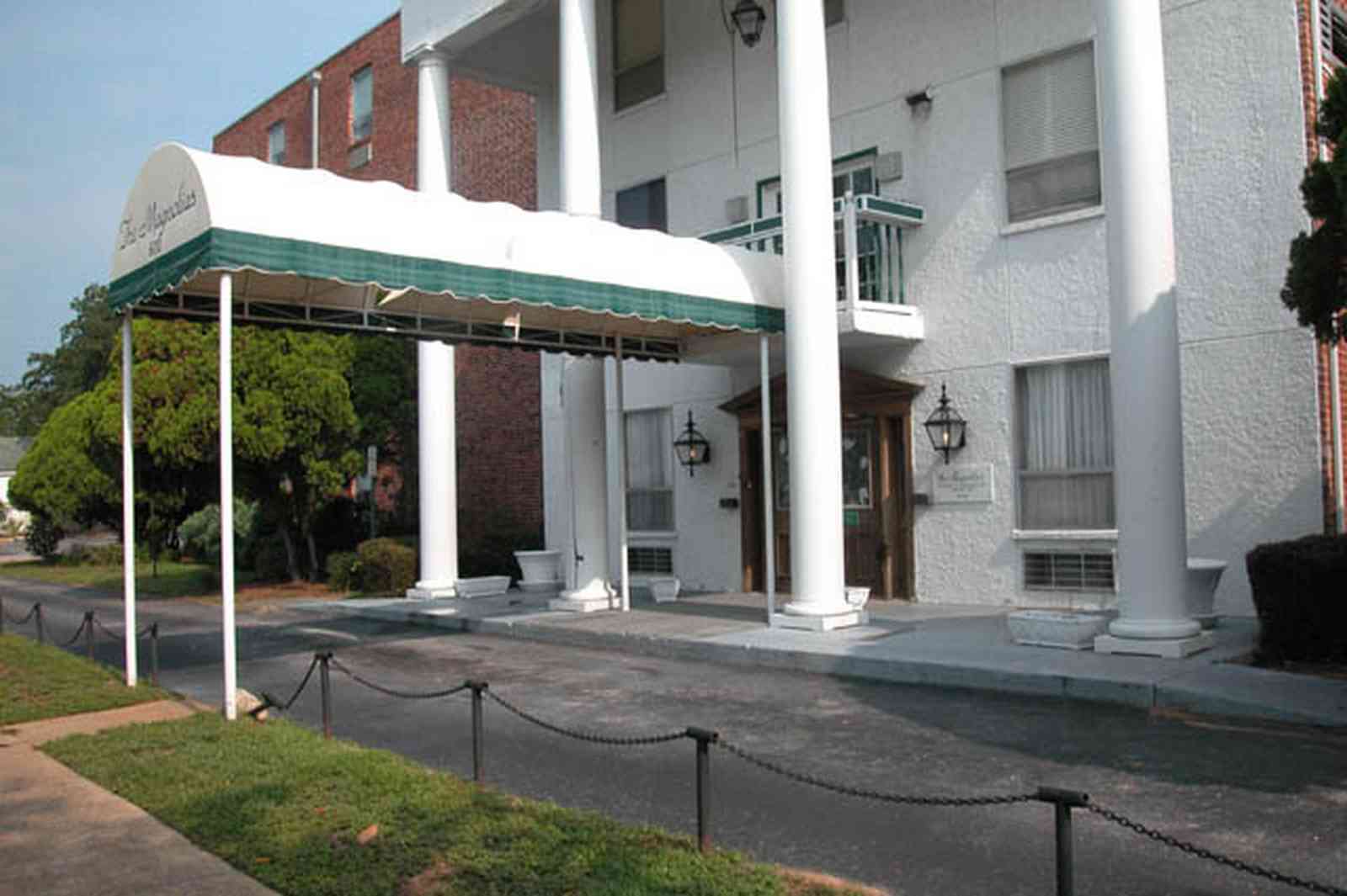 Belmont-Devillers:-The-Magnolias_03.jpg:  magnolia tree, fir tree, columns, brick building, nursing home, apartment building
