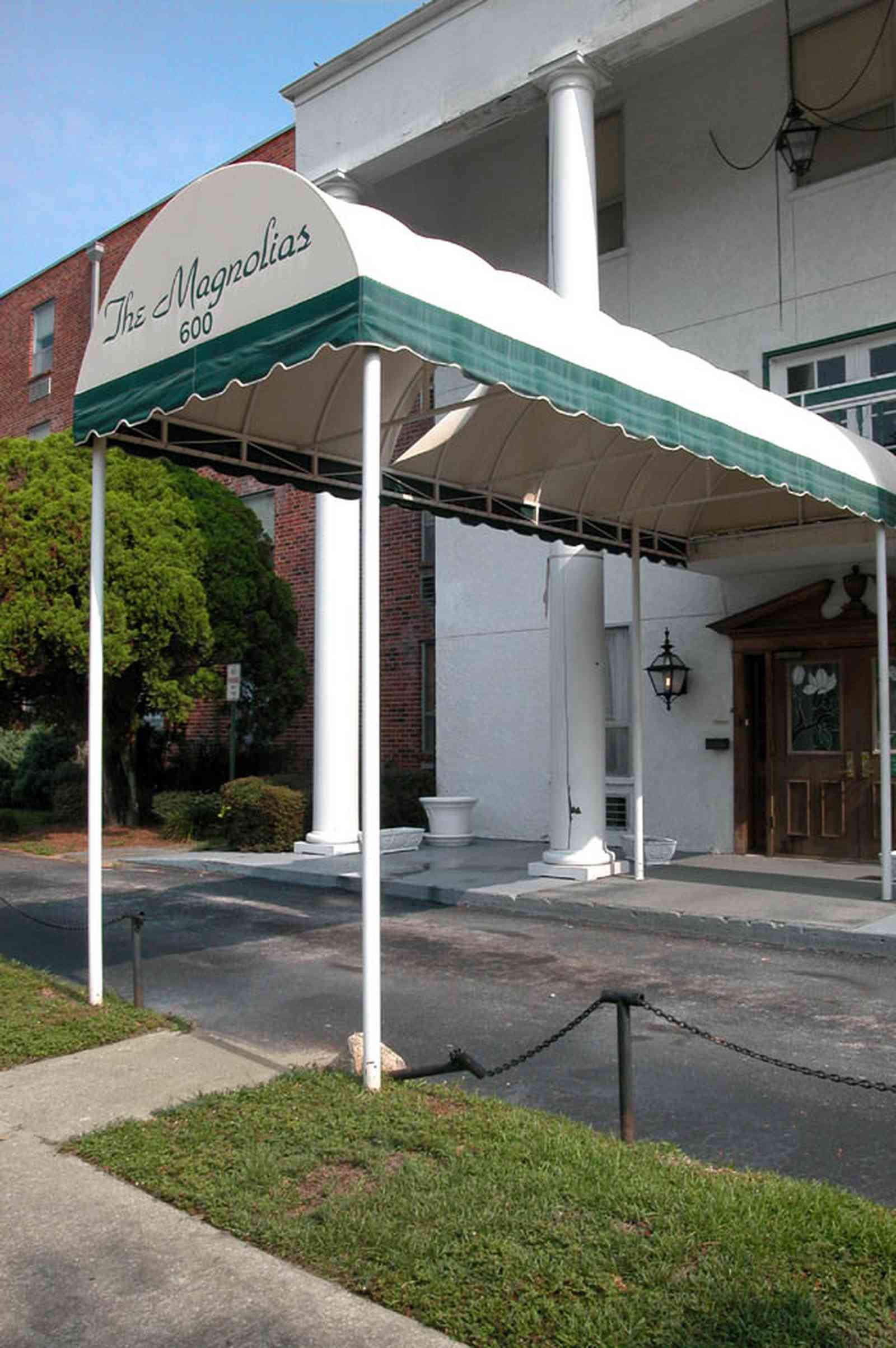 Belmont-Devillers:-The-Magnolias_05.jpg:  magnolia tree, fir tree, columns, brick building, nursing home, apartment building