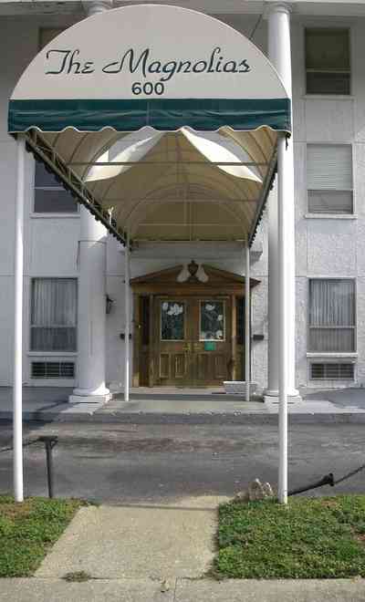 Belmont-Devillers:-The-Magnolias_06.jpg Belmont-Devillers:-The-Magnolias_06.jpg: magnolia tree, fir tree, columns, brick building, nursing home, apartment building