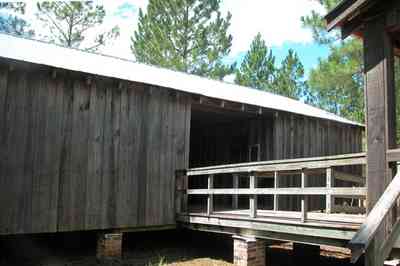 Cantonment:-Roy-Hyatt-Environmental-Center-Dog-Trot-House_05.jpg:  dog trot house, wisteria vine, porch, pine tree, board and batten, brick piers