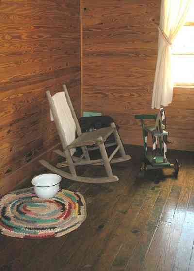 Cantonment:-Roy-Hyatt-Environmental-Center-Dog-Trot-House_11.jpg Cantonment:-Roy-Hyatt-Environmental-Center-Dog-Trot-House_11.jpg: iron bed, quilt, ragdoll, bedroom, wooden walls, wood floor, slop pot, rocking chair