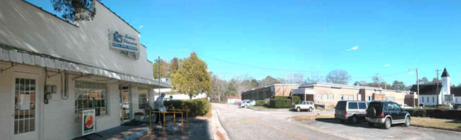 Century:-Pharmacy_02.jpg:  town center, pharmacy, drugstore, church, store front, two-lane road, street