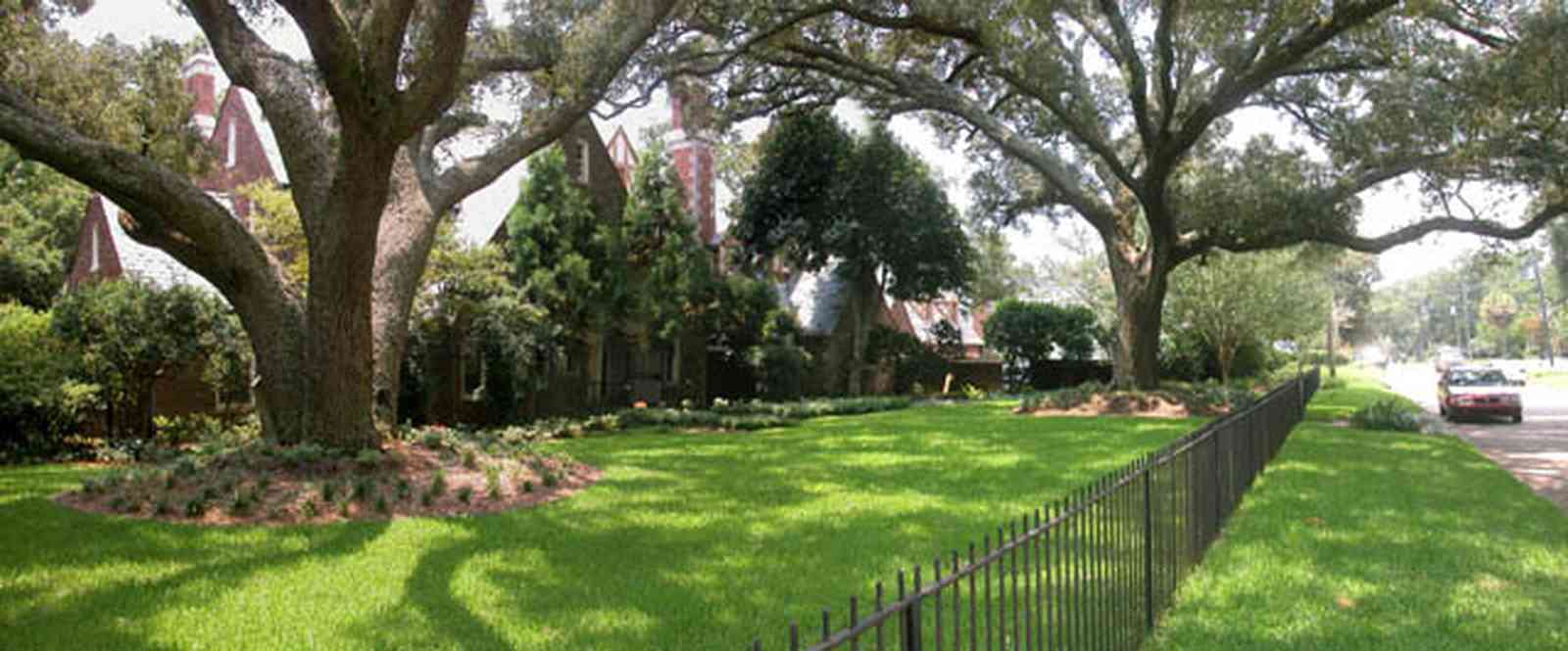 East-Hill:-1919-East-La-Rua-Street_01.jpg:  wrought-iron fence, oak trees, tudor style, oak trees, red brick house, 