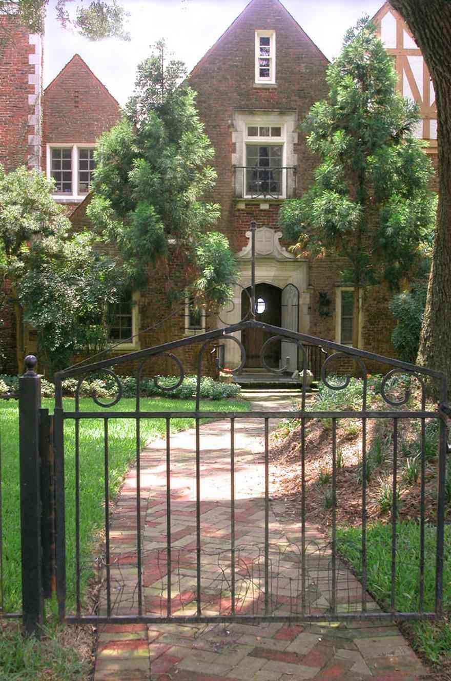 East-Hill:-1919-East-La-Rua-Street_02.jpg:  wrought-iron fence, brick sidewalk, oak trees, tudor house, stone, 