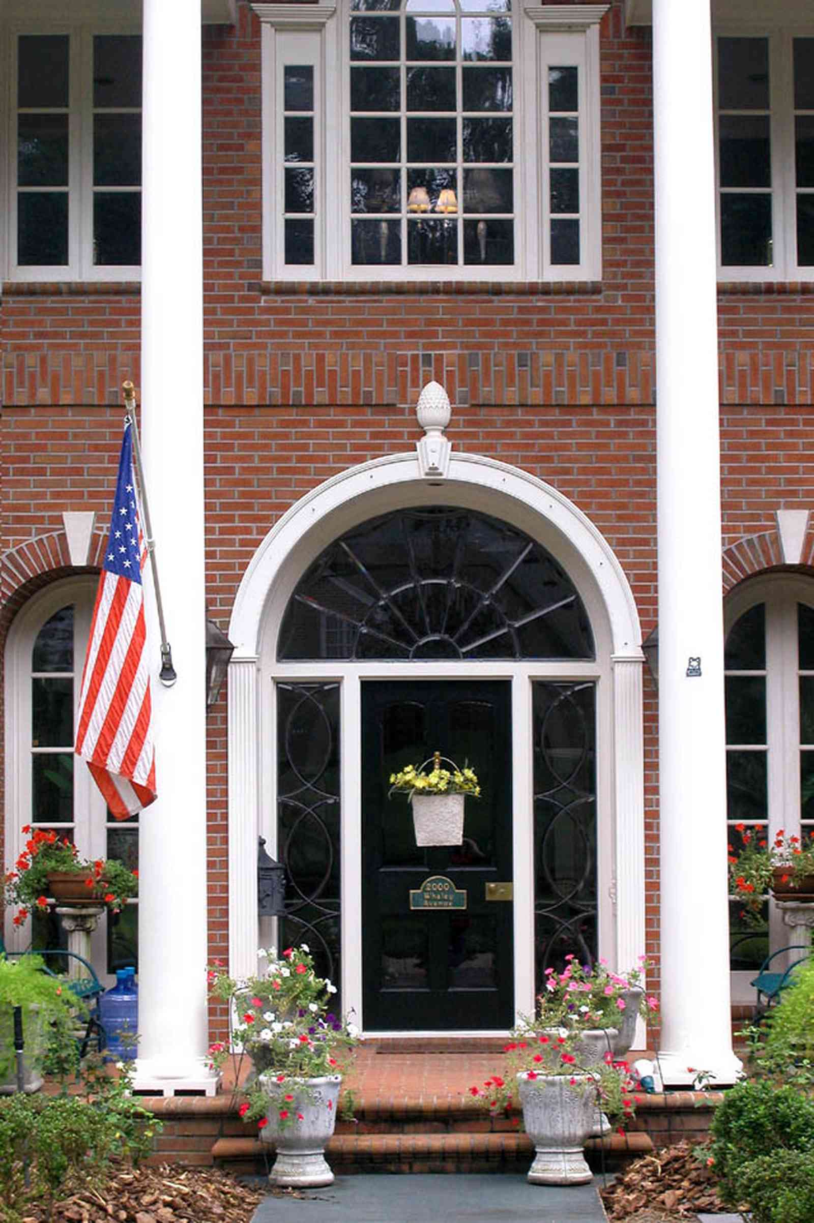 East-Hill:-2000-Whaley-Avenue_04.jpg:  red brick house, impatiens, box hedges, oak trees, columns, shutters, american flag, petunia, ferns, 