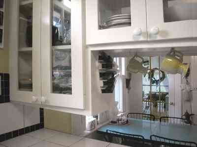 East-Pensacola-Heights:-600-Bayou-Blvd_15.jpg:  glass front cabinets, kitchen, dining area, hanging cups, ceramic tile countertops, screened porch