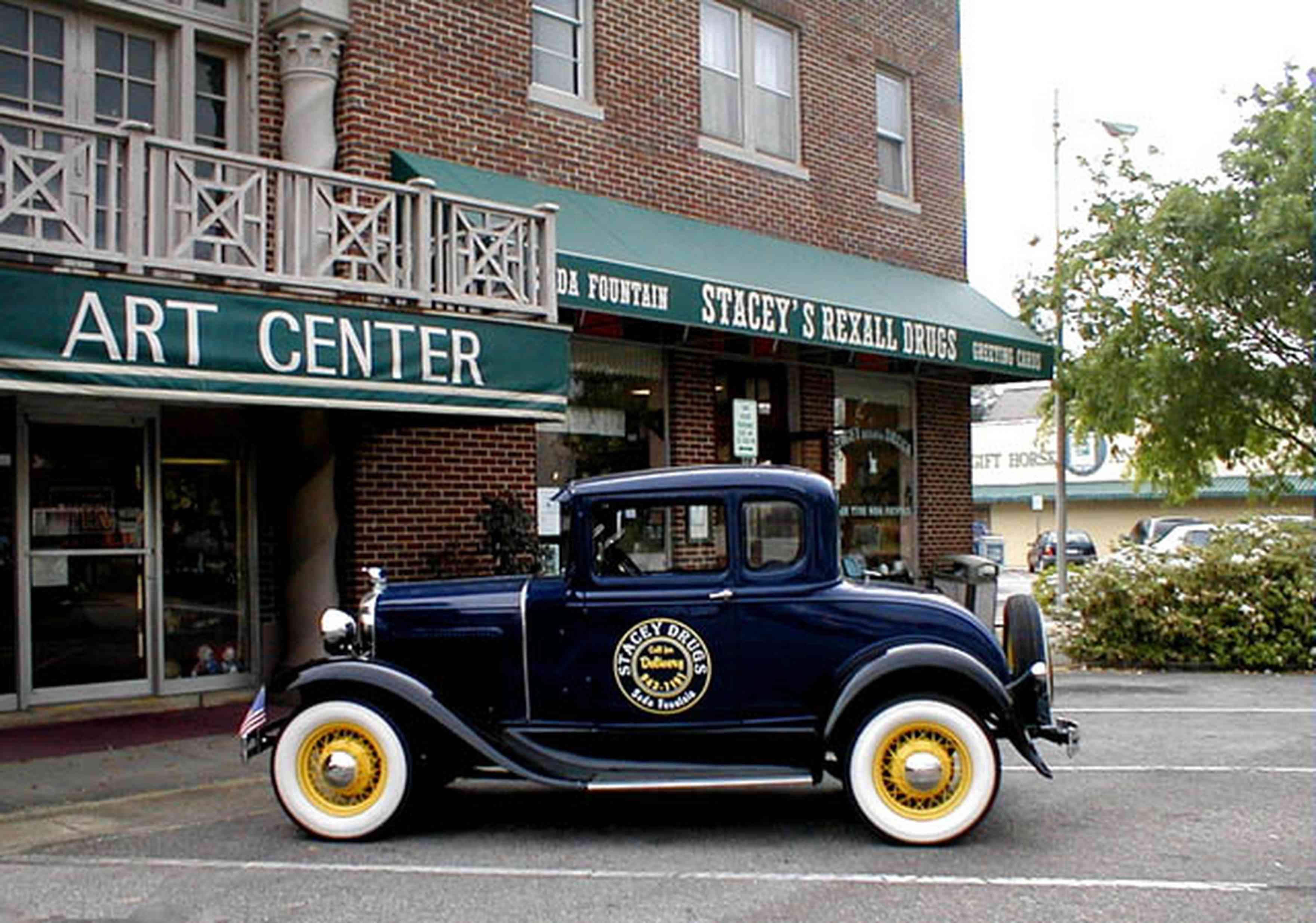 Foley:-Staceys-Drugstore_01.jpg:  drugstore, soda fountain, model-t ford, banana split, glass display cases, soda shop, awning, store front, brick building, art deco architecture, counter, cracker barrel, malts, milkshake, prescription drugs, druggist, card racks