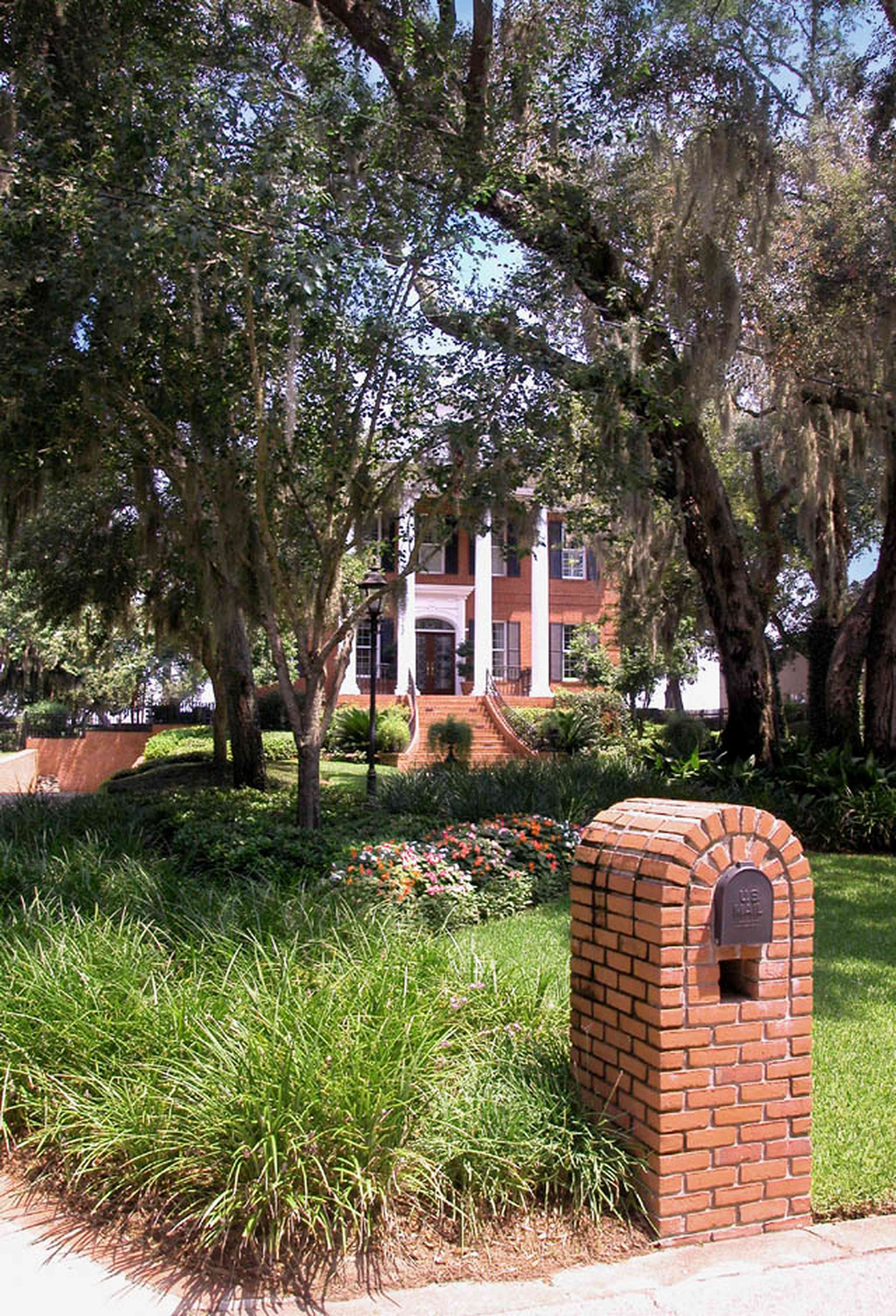 Gulf-Breeze:-506-Kenilworth-Drive_00.jpg:  red brick mansion, white columns, leaded glass door, mailbox, impatiens, brick wall, spanish moss, oak trees, shutters, porch