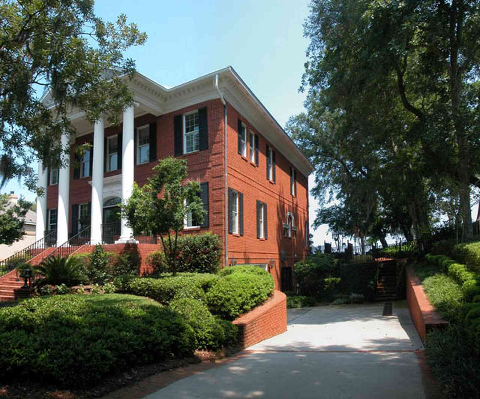 Gulf-Breeze:-506-Kenilworth-Drive_03.jpg:  red brick mansion, white columns, leaded glass door, mailbox, impatiens, brick wall, spanish moss, oak trees, pediment, doric columns, shutters, porch