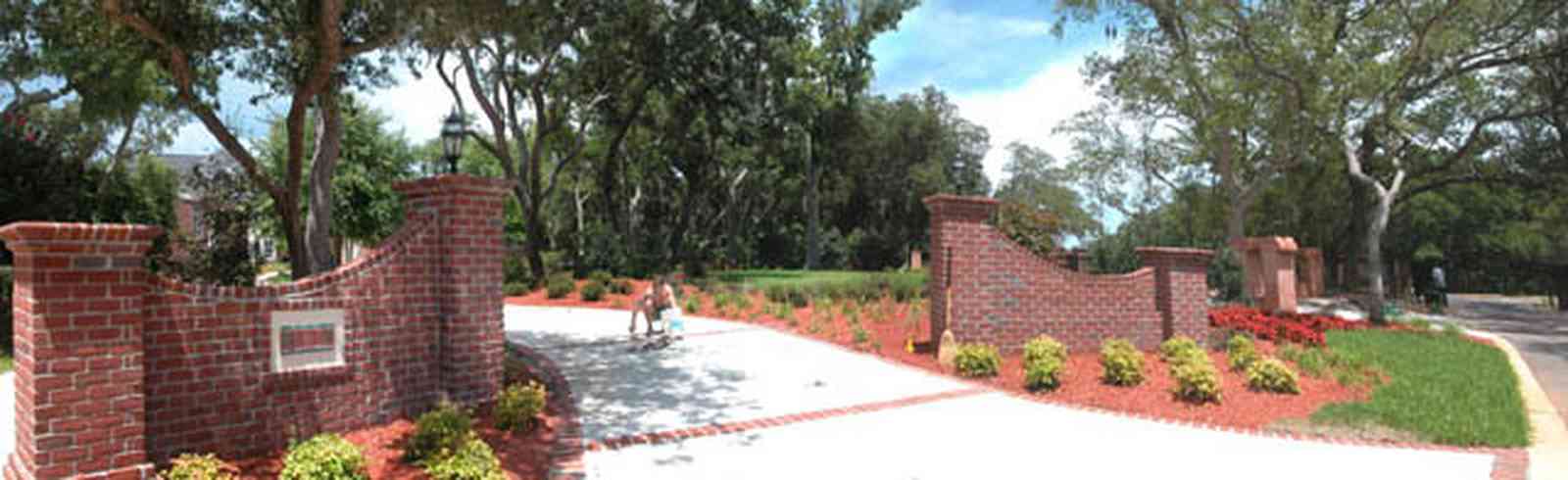 Gulf-Breeze:-706-Fair-Point-Drive_01.jpg:  gate, entrance, formal driveway, lanterns, oak trees, brick columns