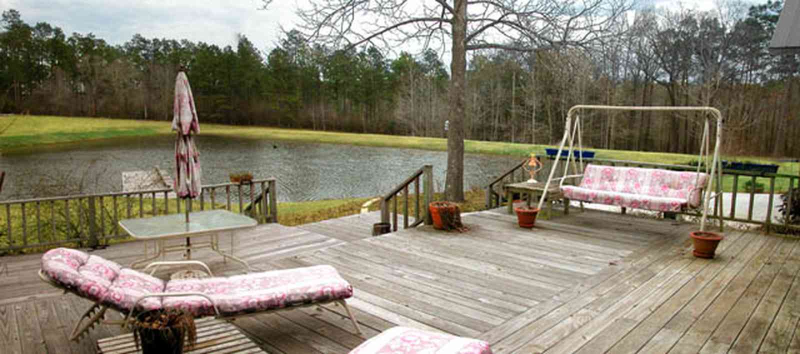 Milton:-Floyd-Farm_03.jpg:  porch, deck, fireplace, log cabin, hills, valley, pond, oak trees, sofa, chaise lounge, umbrella table, lake