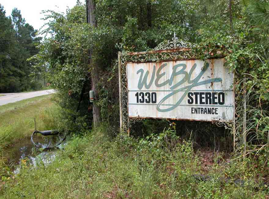 Milton:-WEBY_02.jpg:  sign, wrought iron sign, radio station, pine trees