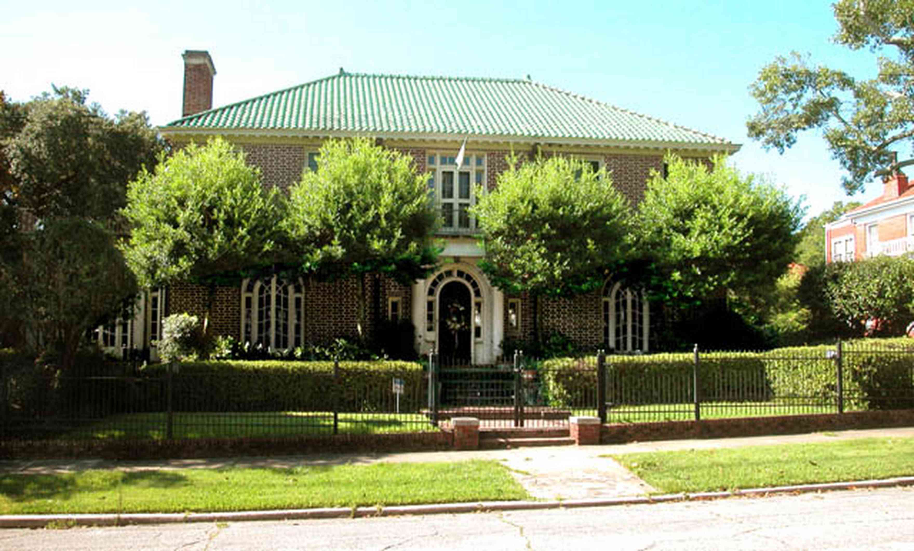 North-Hill:-105-West-Gonzales-Street_01.jpg:  red brick house, fireplace, sidewalk, wrought iron fence, green tile roof