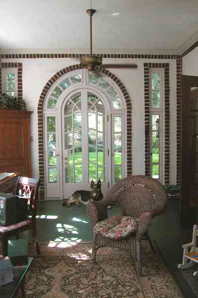 North-Hill:-105-West-Gonzales-Street_09a.jpg:  leaded glass windows, wicker furniture, ceiling fan, brick fireplace, oriental rug, sunroom, german shepard, watch dog