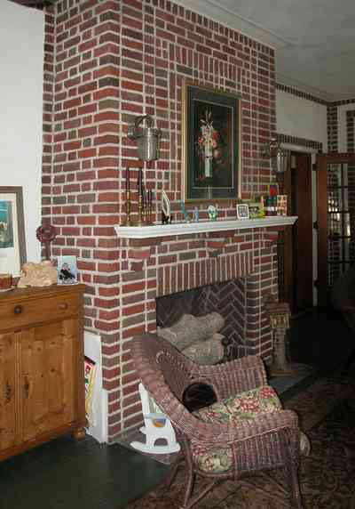 North-Hill:-105-West-Gonzales-Street_09b.jpg:  leaded glass windows, wicker furniture, ceiling fan, brick fireplace, oriental rug, sunroom