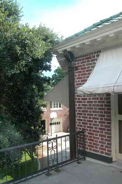 North-Hill:-105-West-Gonzales-Street_20a.jpg:  awning, balcony, side porch, wrought iron railing, oak tree, french colonial architecture, carriage house, basketball goal