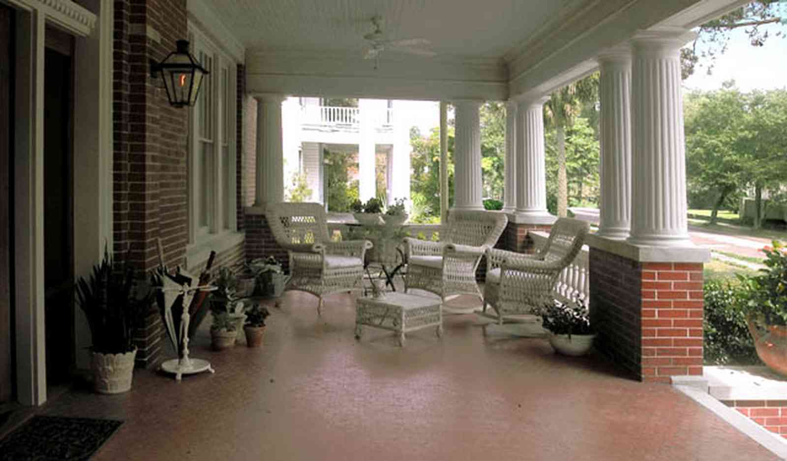 North-Hill:-116-DeSoto-St_02aa.jpg:  white columns, brick pillars, umbrella stand, wicker furniture, hibicus flowers, porch, ceiling fan