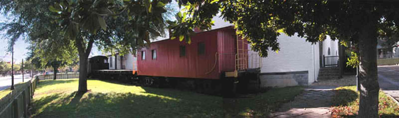 Pensacola:-Historic-Pensacola-Village:-Museum-Of-Industry_01.jpg:  river birch tree, picket fence, museum, warehouse, historic district, caboose, locomotive, train, commerce, industry