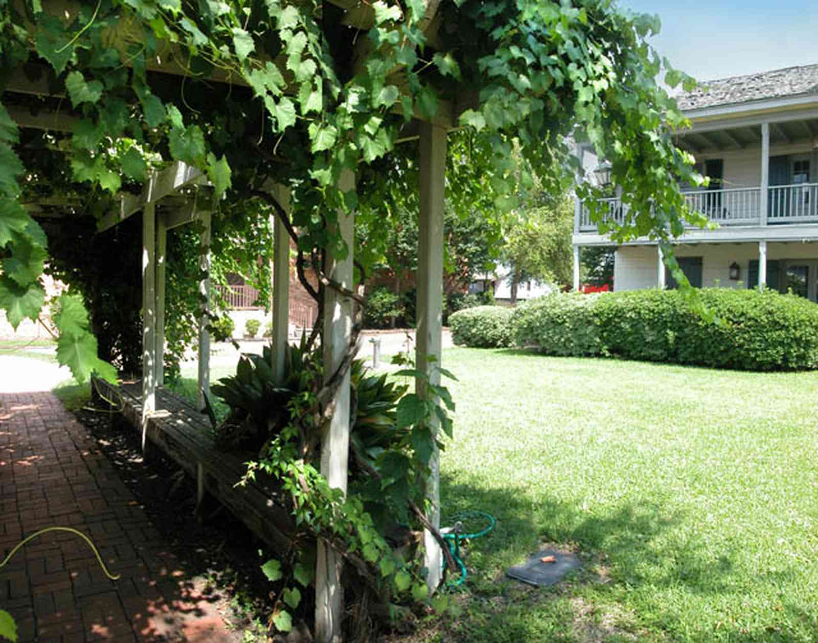 Pensacola:-Historic-Pensacola-Village:-Tivioli-House_01c.jpg:  arbor, grape vine, historic village, historic house, balcony, museum shop, museum, brick sidewalk