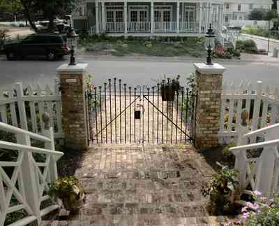 Pensacola:-Seville-Historic-District:-202-Cevallos-Street_02.jpg:  wrought-iron gate, brick pillars, picket fence, brick sidewalk