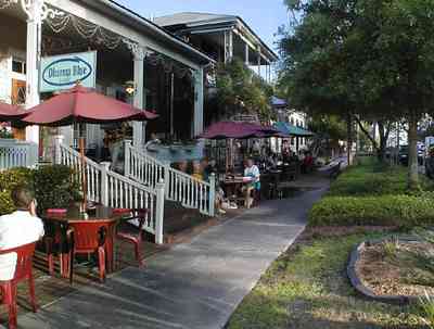 Pensacola:-Seville-Historic-District:-Dharma-Blue-Restaurant_11.jpg:  dining, restaurant, umbrella table, wisteria vine, hanging basket, sidewalk cafe, oak trees