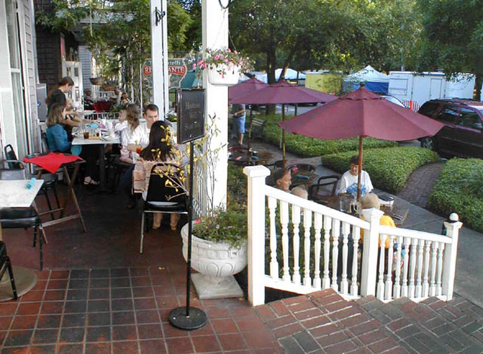 Pensacola:-Seville-Historic-District:-Dharma-Blue-Restaurant_13.jpg:  dining, restaurant, umbrella table, wisteria vine, hanging basket, sidewalk cafe, oak trees