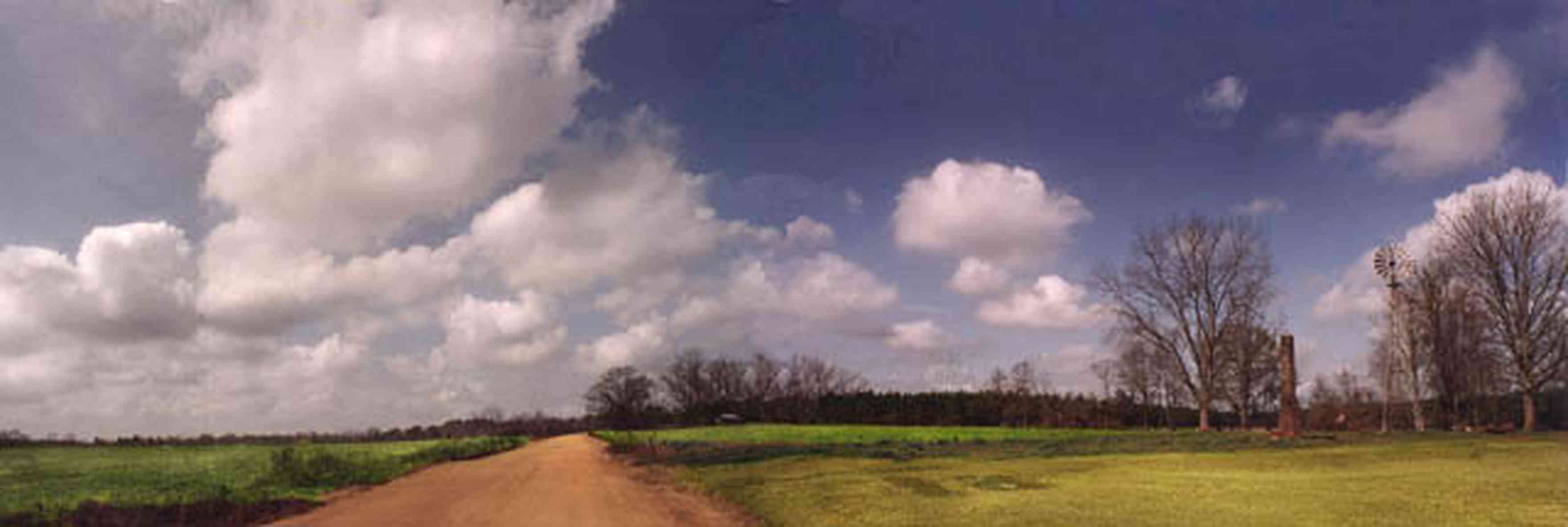 McDavid:-Abandoned-Farm_01.jpg:  country road, dirt road, red clay road, windmill, chimney, cumulus clouds, fields, farmer