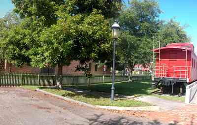 Pensacola:-Historic-Pensacola-Village:-Museum-Of-Industry_03.jpg:  locomotive, caboose, oak tree, picket fence, brick sidewalk
