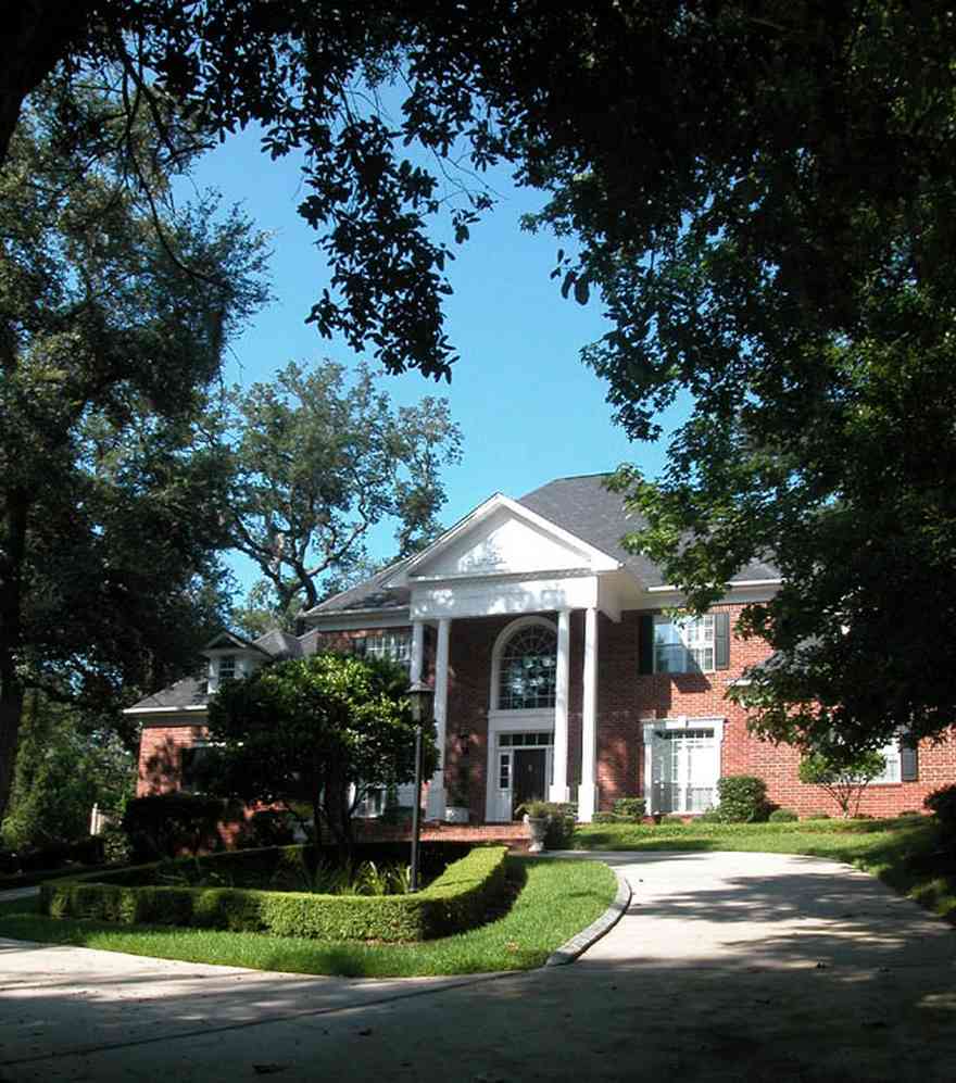 Scenic-Highway:-4641-Canopy-Road_01.jpg:  colonial architectural style, white columns, shutters, crown molding pediment, circular driveway, carriage lamp, sycamore tree, box hedge, oak trees